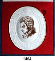 MEDAILLEN AUS PORZELLAN,Staatliche Porzellan-Manufaktur MEISSEN Ohne Ortsangabe Ovale einseitige weiße Porzellanplakette, glasiert, goldener Fadenrand 1978.  Wolfgang Amadeus Mozart.  Brustbild brauner Druck. / Rückseite 10 goldene Textzeilen.  167 x 142 mm.  Im Originaletui.